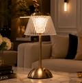 Decorative table lamp with pleated glass shade on a marble surface in a living room setting.