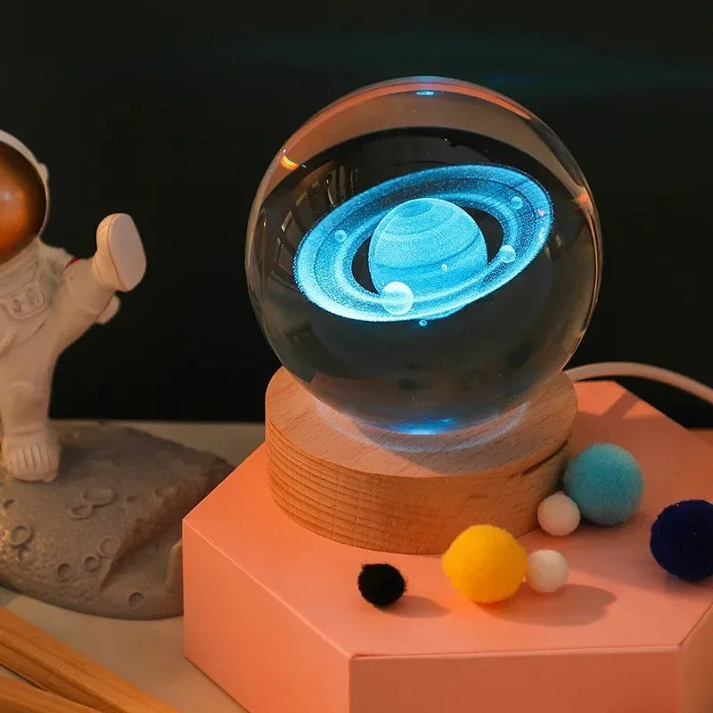 Glass ball with planetary design on a wooden base, surrounded by small colorful balls and a moon-like figure.