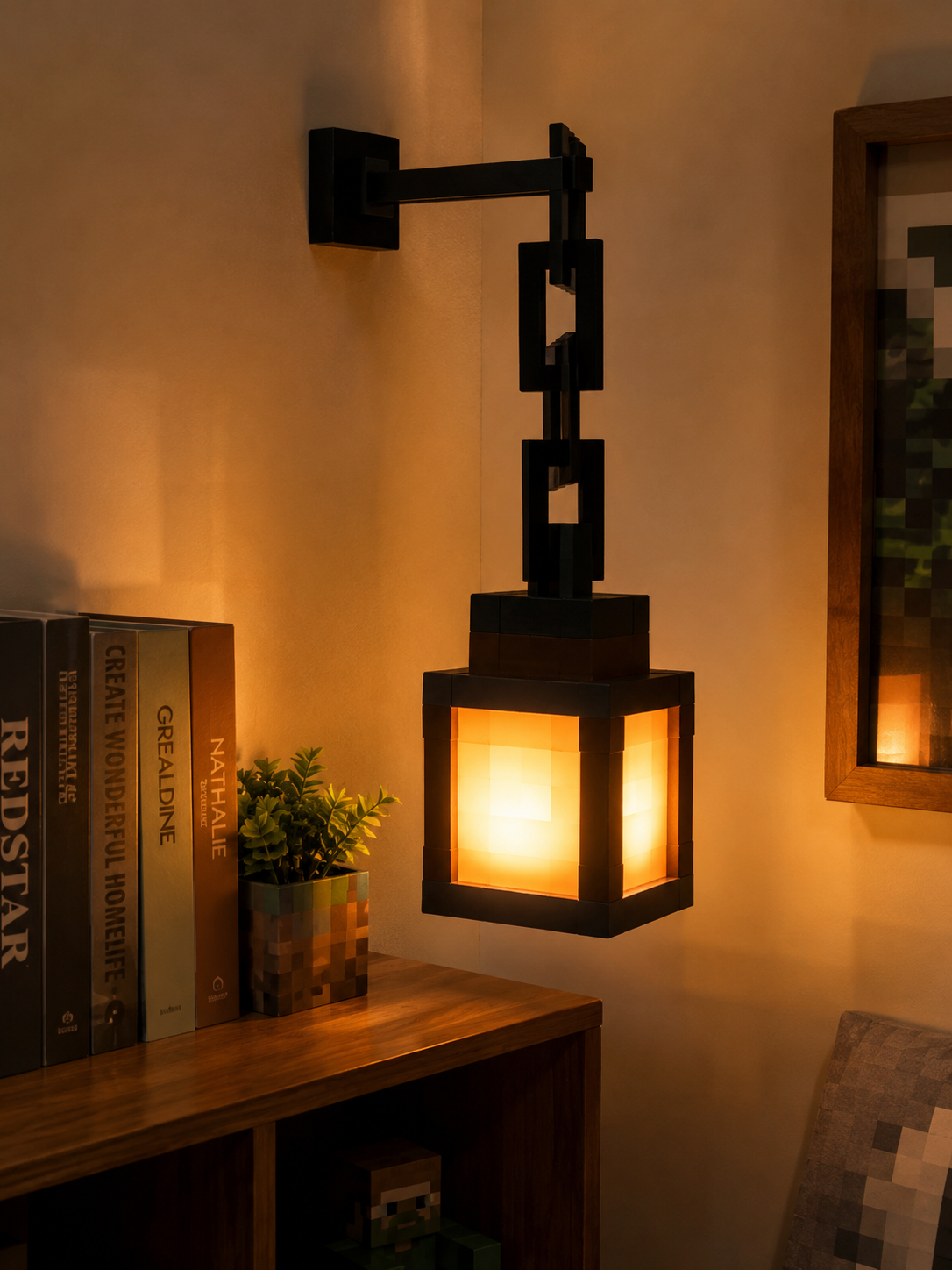 A black metal wall sconce with a glowing warm yellow-orange light inside a square lantern-style shade, mounted on a beige wall above a wooden shelf with books and a small plant.